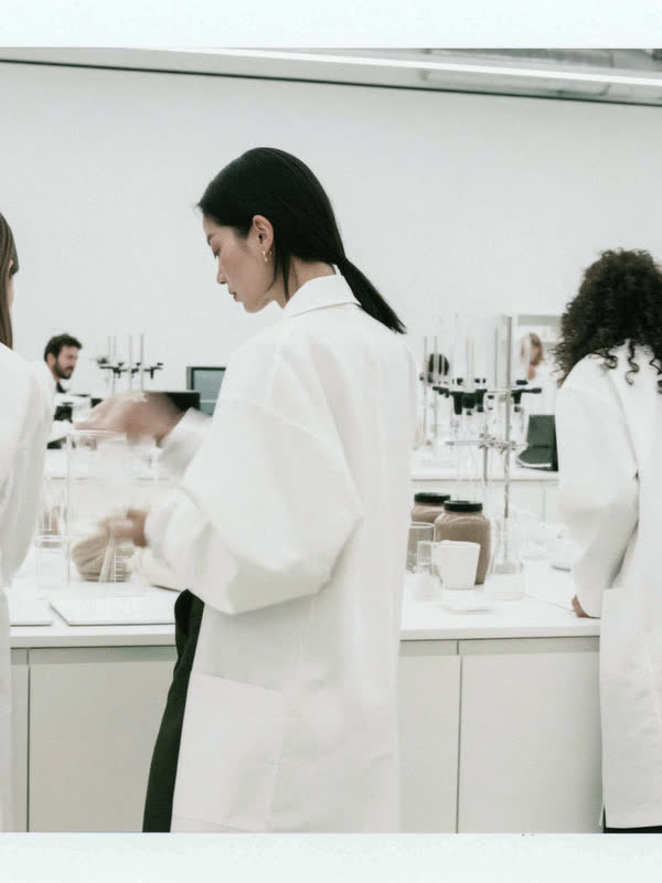 Três cientistas manipulando vidraria em uma bancada de laboratório.
